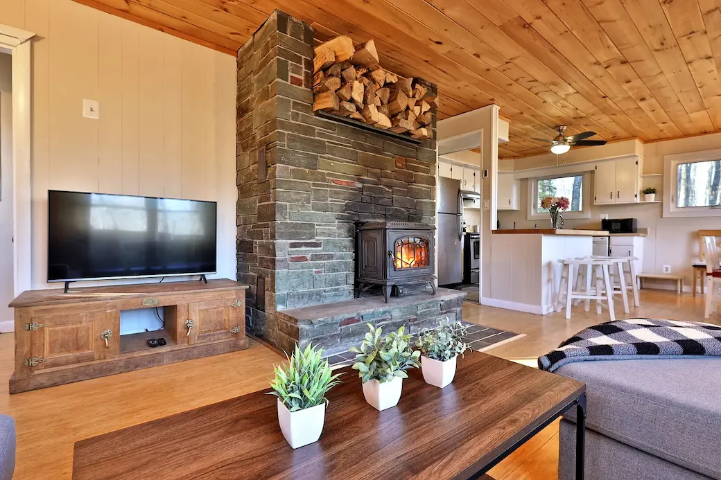 Vacation rental duplex's view of a living room with wood-burning fireplace, flat screen TV, and integrated kitchen